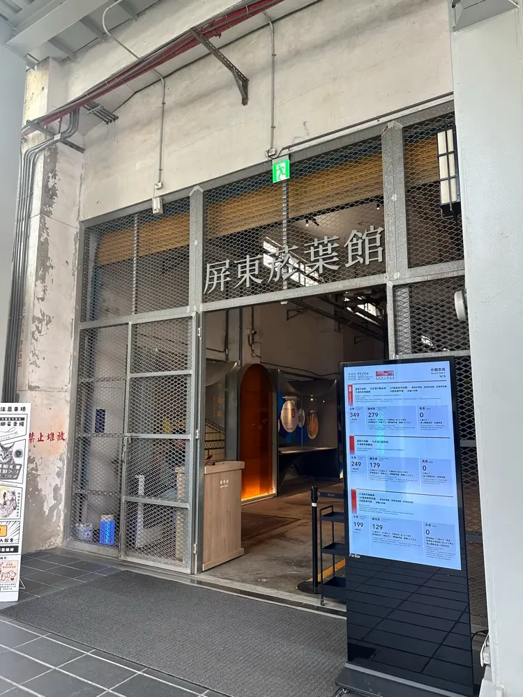 屏東菸葉館入口，有著斑駁的工業風鐵網門與現代化的電子售票看板